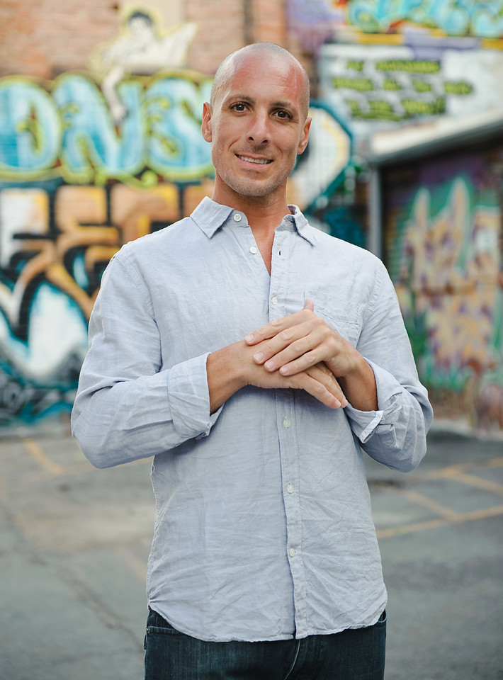 Gabe Yoga &mdash; a warm portrait, hands resting at his chest, looking to camera